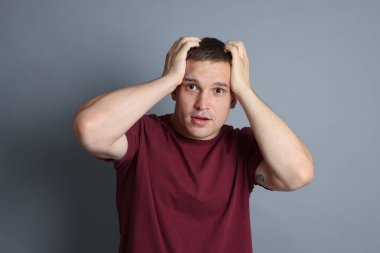 Gri arka planda panik atak geçiren bir adam.