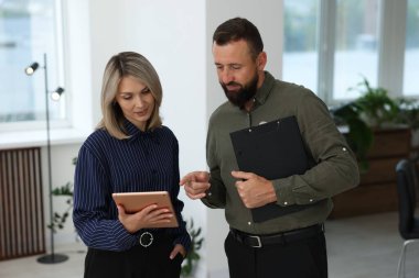 Tablet ve pano ile gülümseyen iş ortakları ofiste birlikte çalışıyorlar.