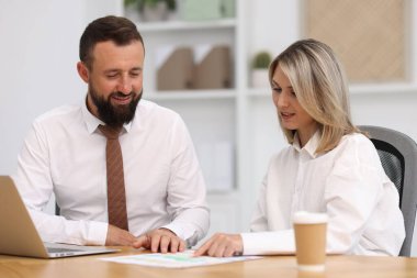 Ofisteki belgelerle çalışan gülümseyen iş ortakları