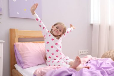 Küçük kız evde yatakta uyanıyor.