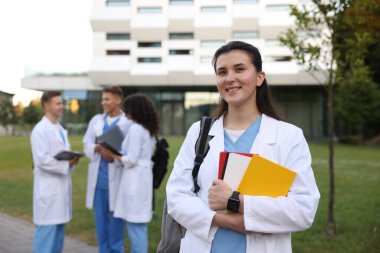 Dışarıda defterleri olan üniformalı bir tıp öğrencisi. Seçici bir odak noktası.
