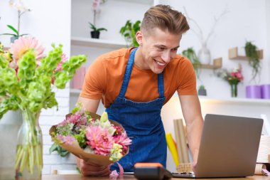 Dükkandaki ahşap masada çalışan bir buket çiçekli profesyonel çiçekçi.