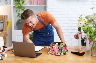 Dükkandaki ahşap masada çalışan bir buket çiçekli profesyonel çiçekçi.