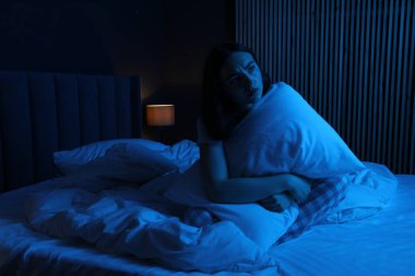 Evde yatağında uykusuzluk çeken, yastıklı hayal kırıklığına uğramış bir kadın.