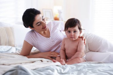 Anne küçük sevimli bebeğini yatağın içine yatırmış.