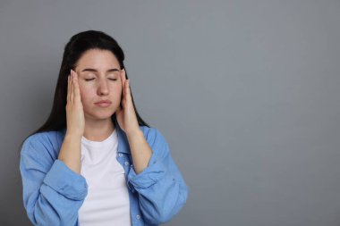 Panik atak. Gri arka planda kendini sakinleştiren kadın, mesaj için alan