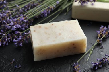 Aromatik sabun barı ve lavanta çiçekleri koyu dokulu masa üzerinde, yakın plan.