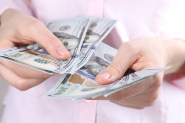 Açık gri arka planda dolar banknotları sayan kadın, yakın plan