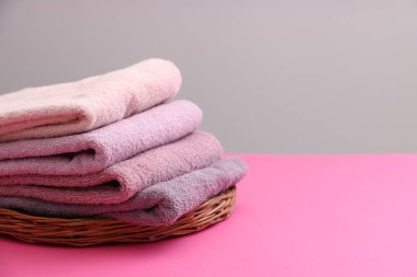 Pembe masadaki yumuşak havlu yığını gri arka plana karşı, yakın plan. Metin için boşluk