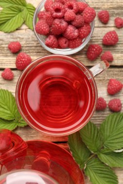 Lezzetli ahududu çayı, böğürtlen ve yapraklar ahşap masada, düz uzanmış