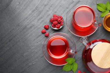 Cam fincanlarda Aromatik ahududu çayı, çaydanlık, böğürtlen, yeşil yapraklar ve siyah masada bal, düz yatak. Metin için boşluk