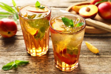 Bardakta buzlu şeftali çayı ve ahşap masada taze meyve, yakın plan.