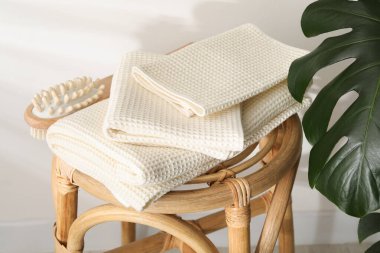 Waffle havluları ve hasır koltukta masaj fırçası, ışık duvarının yanında, yakın plan.