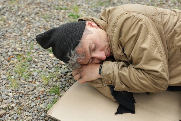 Homeless man sleeping on carton in park