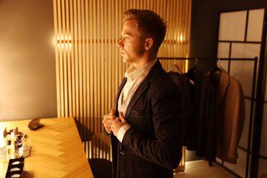 Şık giyinmiş bir adam içeride hazırlanıyor.