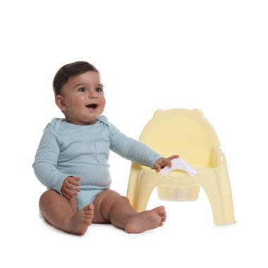 Beyaz arka planda lazımlığın yanında oturan şirin bebek.