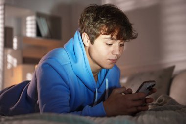 Ergen çocuk evde akıllı telefon kullanıyor.