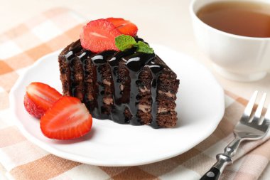 Çilek, çay ve çatalla servis edilen çikolatalı kek, yakın plan.