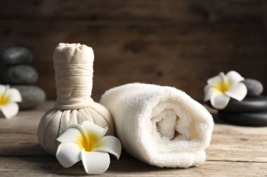 Bitki torbası, havlu, spa taşları ve ahşap masa üzerindeki tesisat çiçekleri, yakın plan.