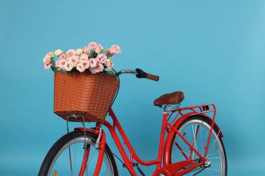 Açık mavi arka planda güzel çiçeklerle dolu bir bisiklet sepeti