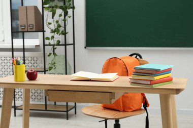 Farklı okul kırtasiyesi ve kırmızı elma, kapalı alanda tahtaya yakın ahşap masada.