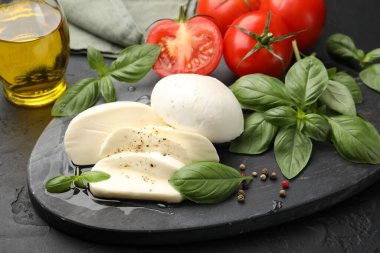 Lezzetli mozzarella peyniri, domates, fesleğen, karabiber ve yağ, yakın plan.