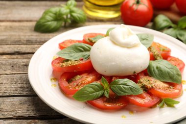 Caprese salatası, ahşap masada pesto sosuyla servis edilir.