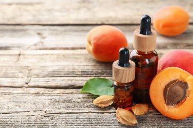 Gerekli yağ şişeleri, taze kayısılar, çekirdekler ve ahşap masa üzerinde yeşil yaprak, yakın çekim. Metin için boşluk