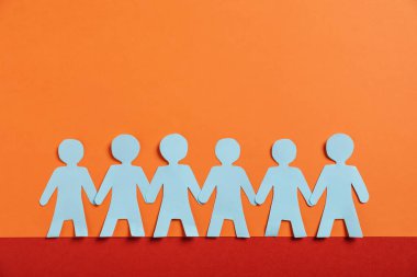 Renkli arka planda el ele tutuşan insan kağıt figürleri, düz yatış. Metin için boşluk