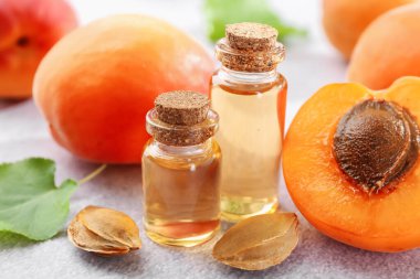 Şişelerdeki, tohumlardaki ve olgun kayısılardaki yağlar açık dokulu masalarda, yakın çekim.