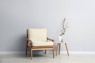 Açık gri duvarın yanında rahat bir koltuk ve dekor.