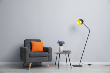 Açık gri duvarın yanında rahat bir koltuk ve dekor.