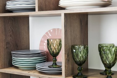 Beyaz duvarın yanında farklı plaka ve gözlüklerle raflama ünitesi, yakın plan.