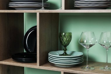 Kapalı alanda yeşil duvarın yanında farklı plakalı ve gözlüklü raf ünitesi.