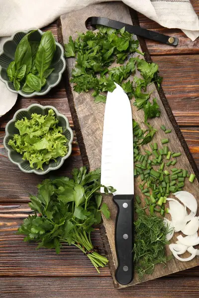 Farklı taze otlar, baharatlar ve bıçaklar ahşap masada, düz yerde.