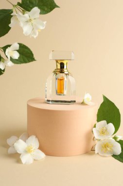 Bir şişe parfüm ve bej arka planda yasemin çiçekleri.