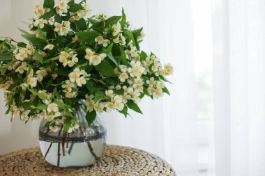 Güzel yasemin çiçekleri vazonun içinde pencerenin yanındaki hasır masada, metin için yer var.