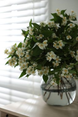 Güzel yasemin çiçekleri vazonun içinde pencerenin yanındaki masada, yakın plan.