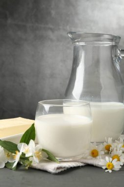 Gri ahşap masadaki taze süt ürünleri ve çiçekler dokulu arka plana karşı, yakın plan