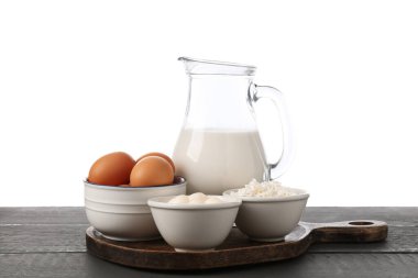 Gri ahşap masada beyaz arka planda farklı süt ürünleri ve yumurtalar