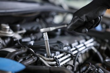 Otomobil parçaları. Tork anahtarı olan profesyonel bir tamirci, kapalı alanda araba tamir ediyor, yakın plan.
