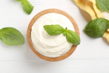 Lezzetli yoğurt kasede ve fesleğen beyaz ahşap masada, düz yerde.