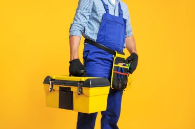 Turuncu arka planda alet kutusu olan profesyonel tamirci, yakın plan.