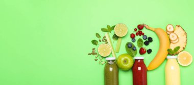Süper yemek. Cam şişelerdeki lezzetli içecekler ve yeşil arka plandaki malzemeler, düz yatak. Metin için boşluk