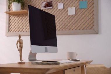 Ev ofisinde bilgisayar, kırtasiye ve insan figürlü ahşap masa, yakın plan. İç tasarım