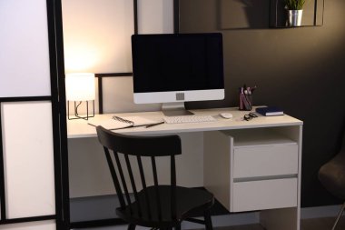 Çalışma masası, bilgisayarı ve kırtasiyesi olan şık bir iş yeri. İç tasarım