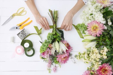 Çiçek buketi yapan bir çiçekçi, beyaz ahşap masa, üst manzara