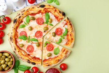 Açık yeşil arka planda nefis kesilmiş pizza ve malzemeler. Metin için boşluk
