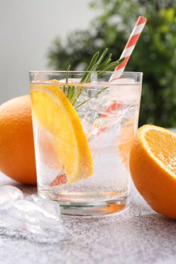 Portakal dilimli soda ve gri masada biberiye, yakın plan.