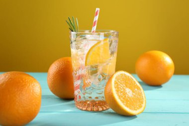 Açık mavi ahşap masada buzlu ve portakallı soda tazeleniyor.